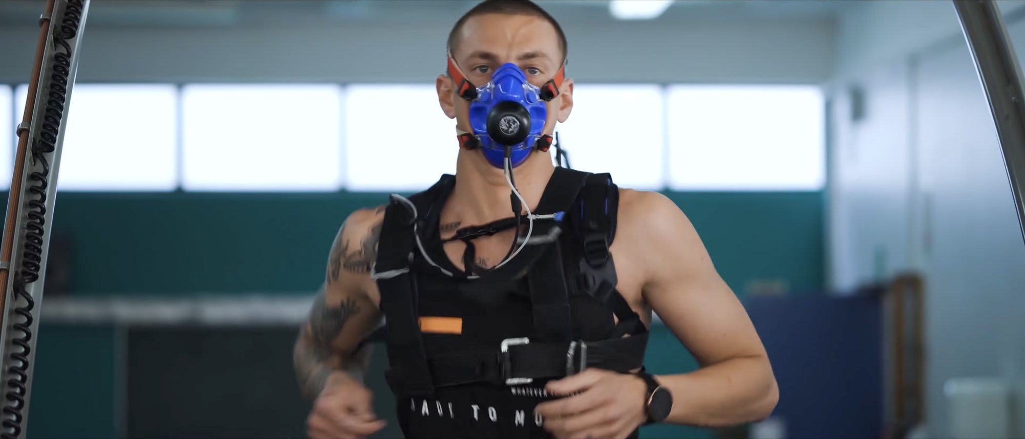 Simon Stofberg mid VO2 max test, oxygen mask and weighted vest, eyes on the camera