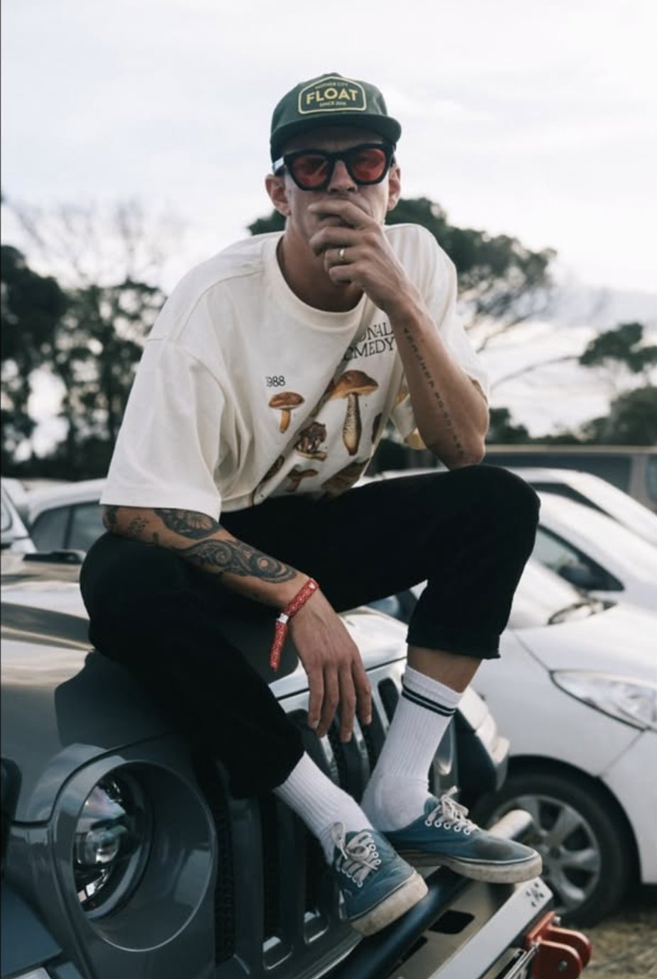 Simon Stofberg sitting on a Jeep bonnet in a Float cap and red glasses